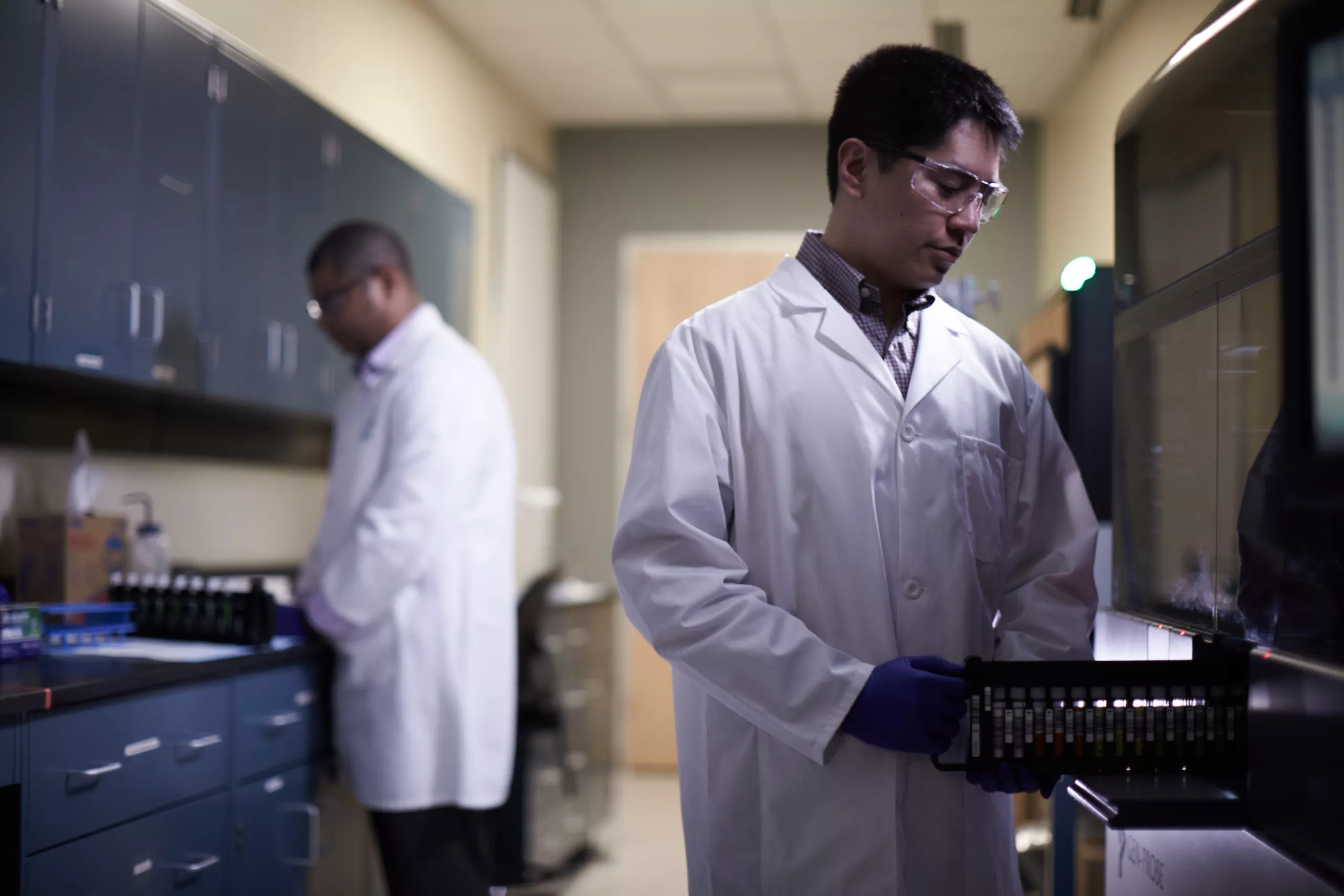 Lab technician pushing tray of vials into medical system